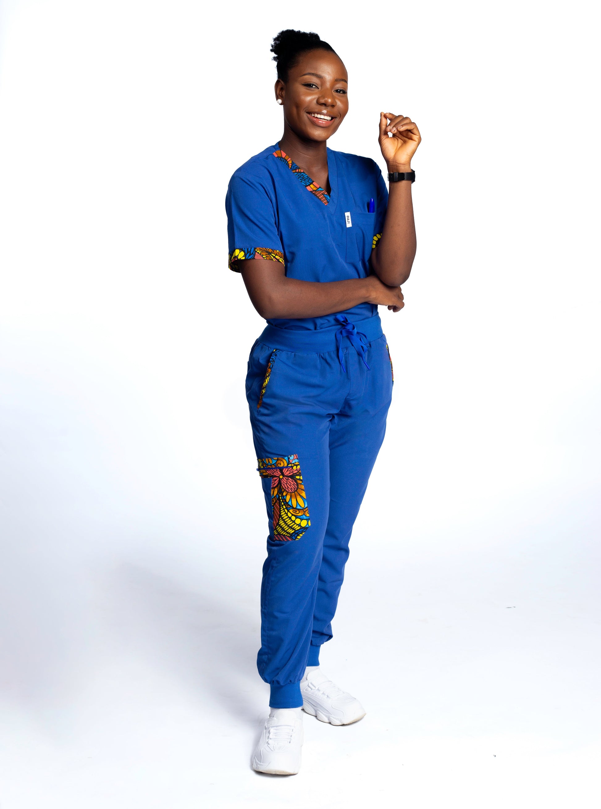 Person wearing a blue scrubs outfit with colorful designs on a white background