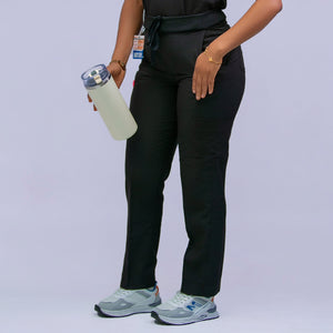 Person wearing a black medical uniform with a stethoscope, holding a water bottle on a light gray background