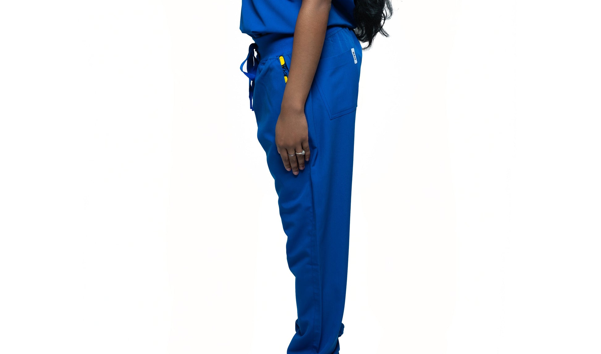 A person standing sideways, wearing blue jogger pants with a visible pocket and a small yellow detail on the waistband.