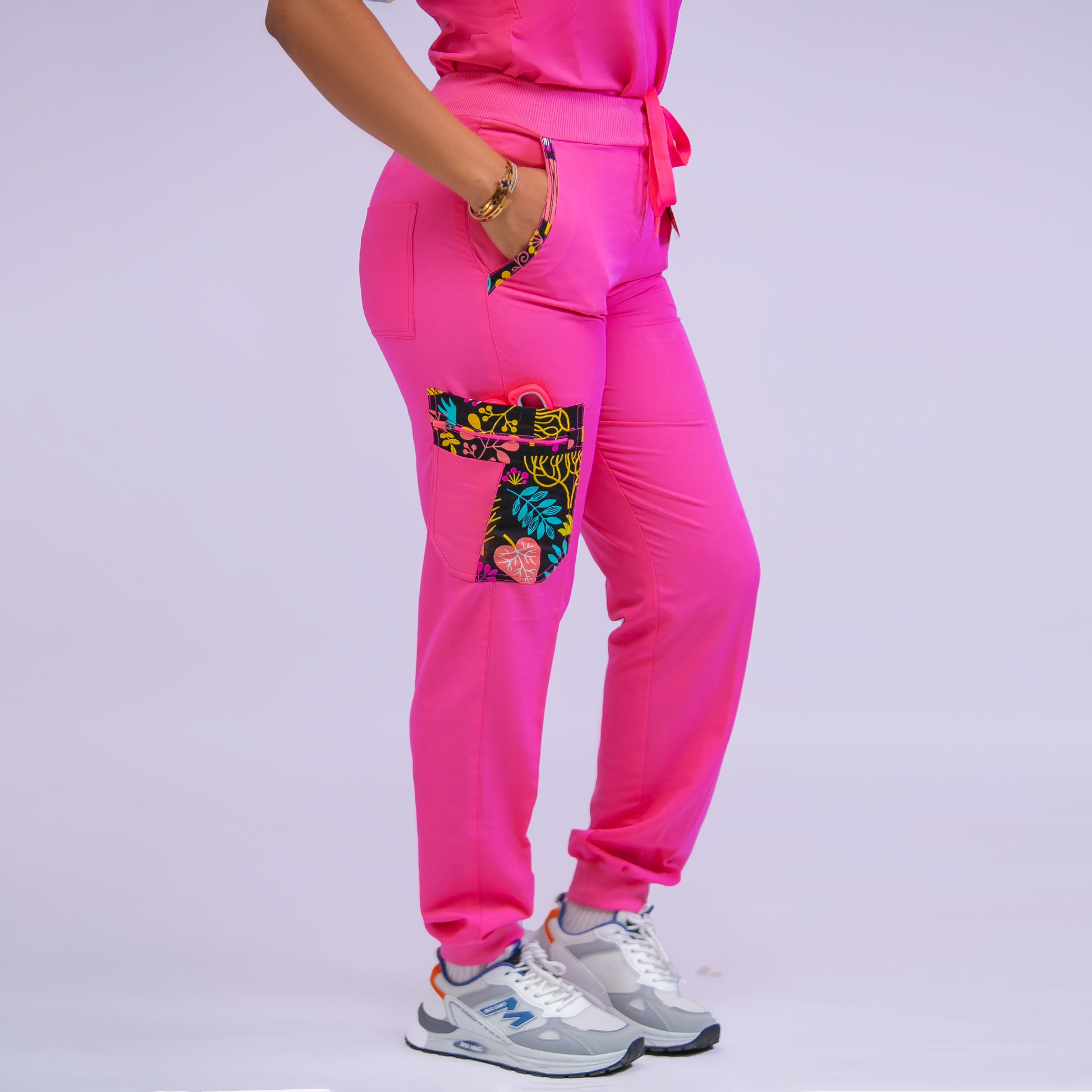 Person wearing bright pink jogger pants with a colorful pocket design on a light purple background