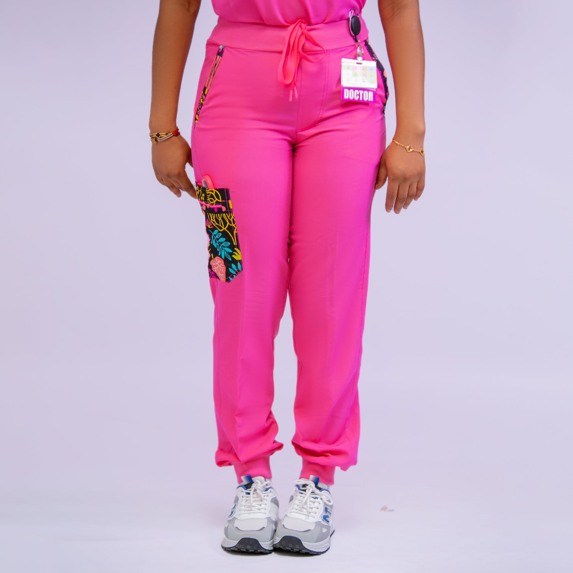 Person wearing bright pink pants with colorful pocket designs on a light gray background