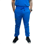 A person wearing blue Dara scrub jogger pants with a drawstring waist and pockets, paired with a blue top and black shoes.