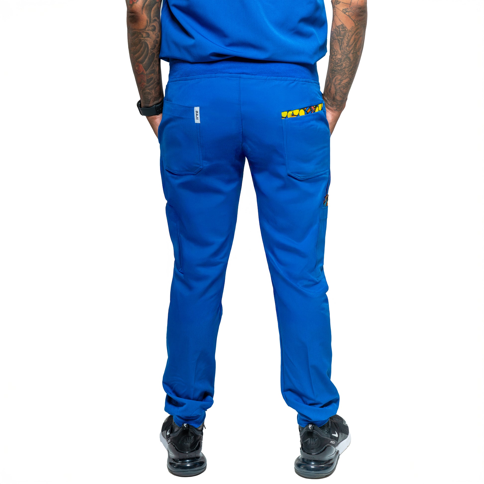 A person wearing blue Dara scrub jogger pants with a drawstring waist and pockets, paired with a blue top and black shoes.