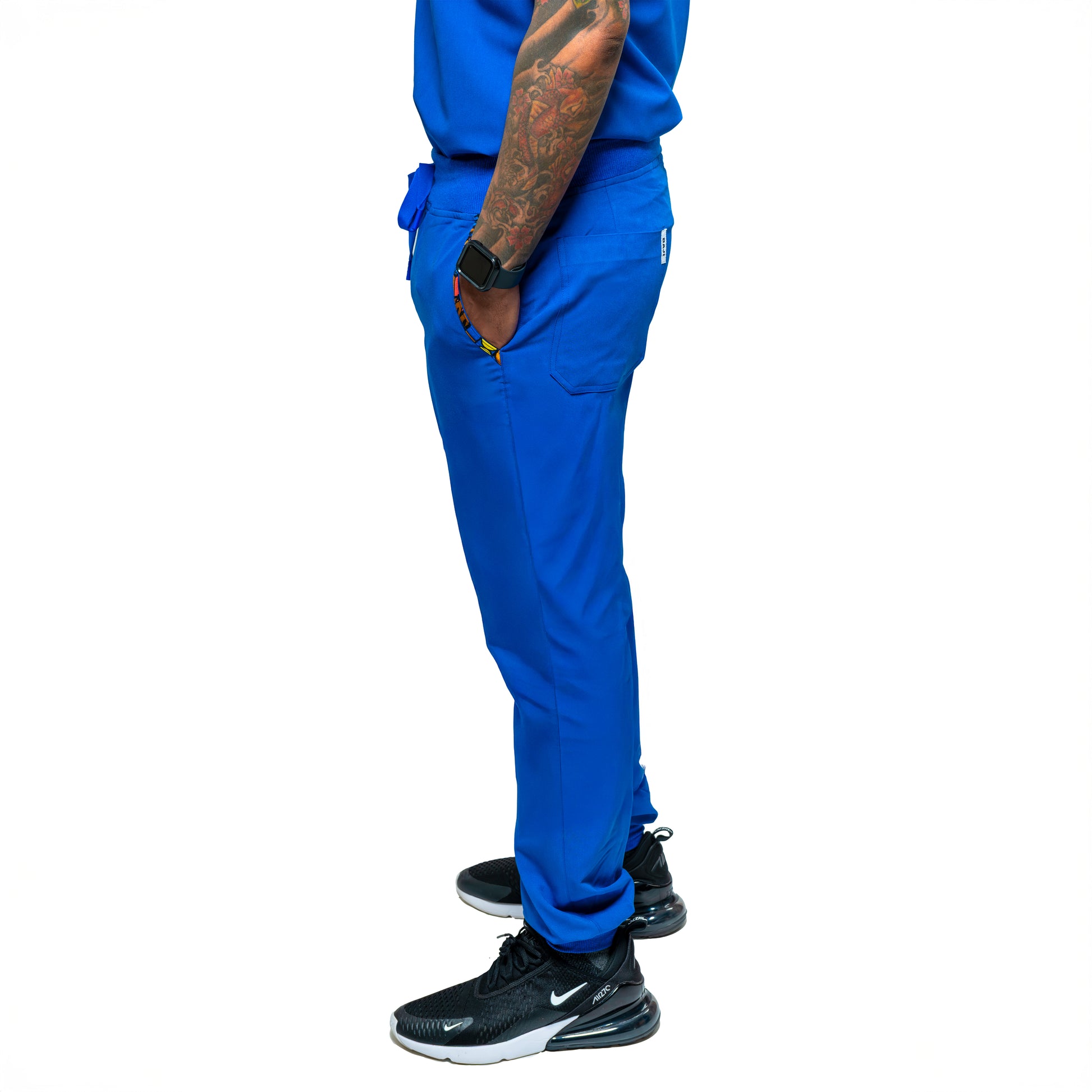 A person wearing blue Dara scrub jogger pants with a drawstring waist and pockets, paired with a blue top and black shoes.