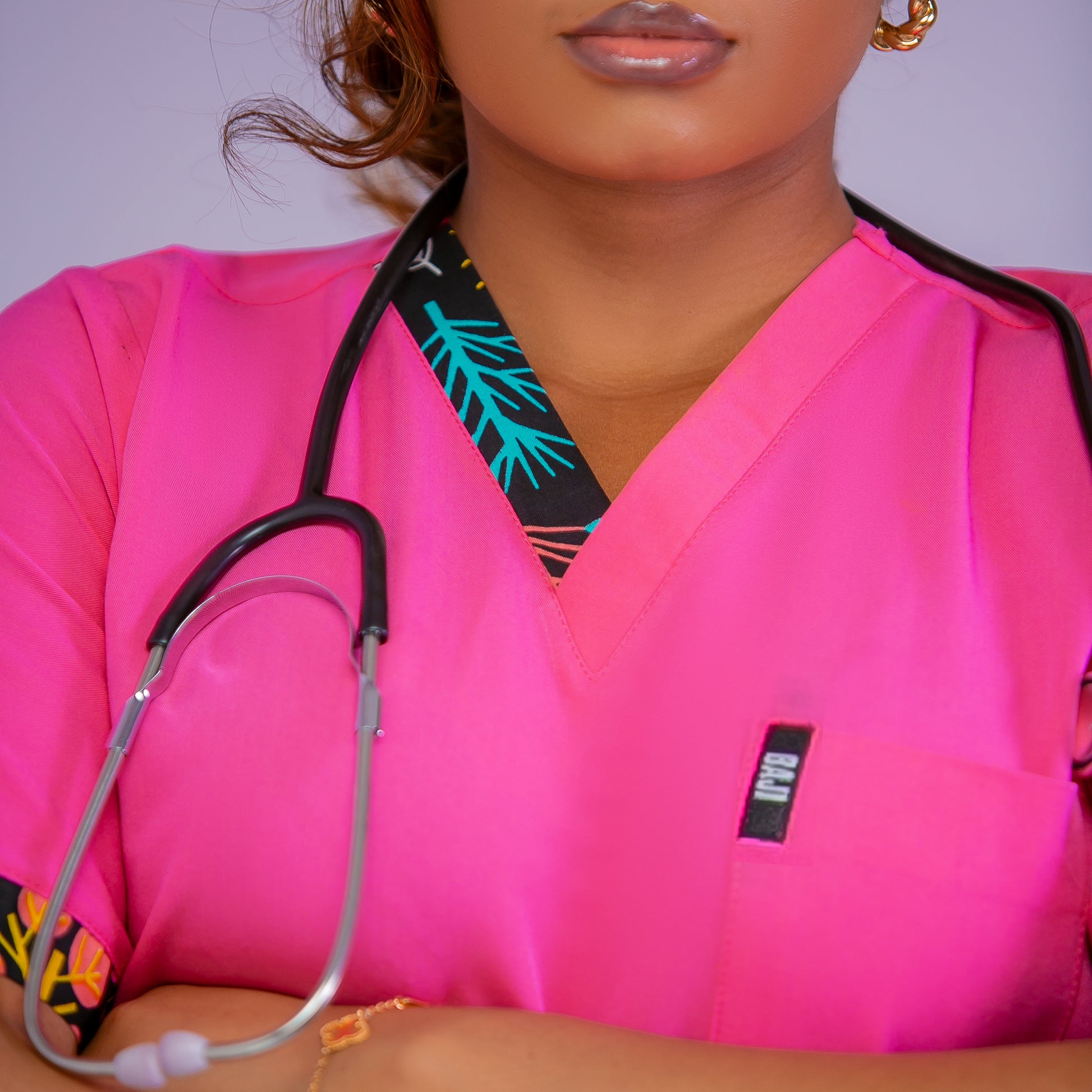 Person wearing pink scrubs with a stethoscope around their neck against a plain background