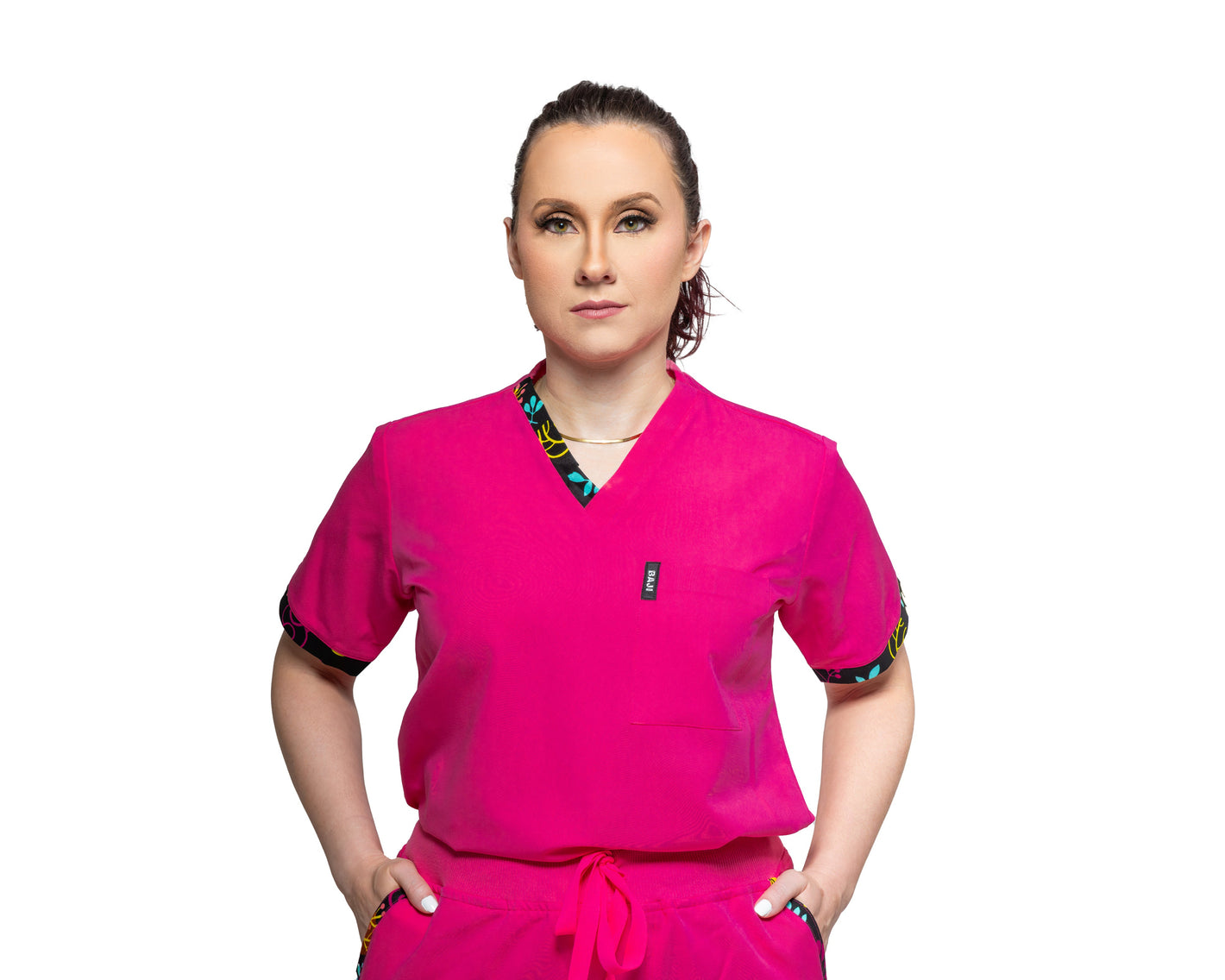 A female model wearing a Pink V-neck scrub top with a single chest pocket.