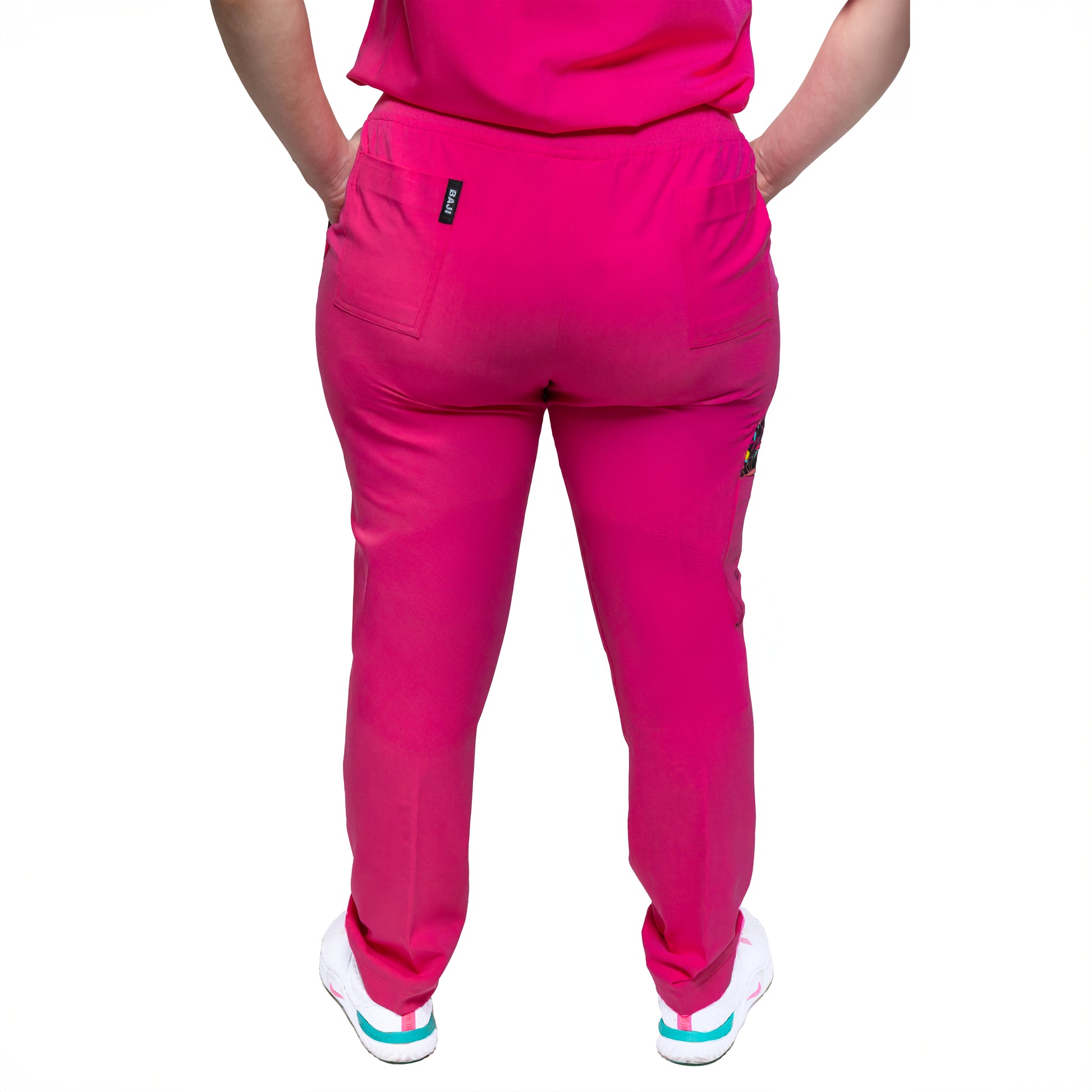 A person wearing pink female Nia Scrub Pant with decorative detail on the knee area.