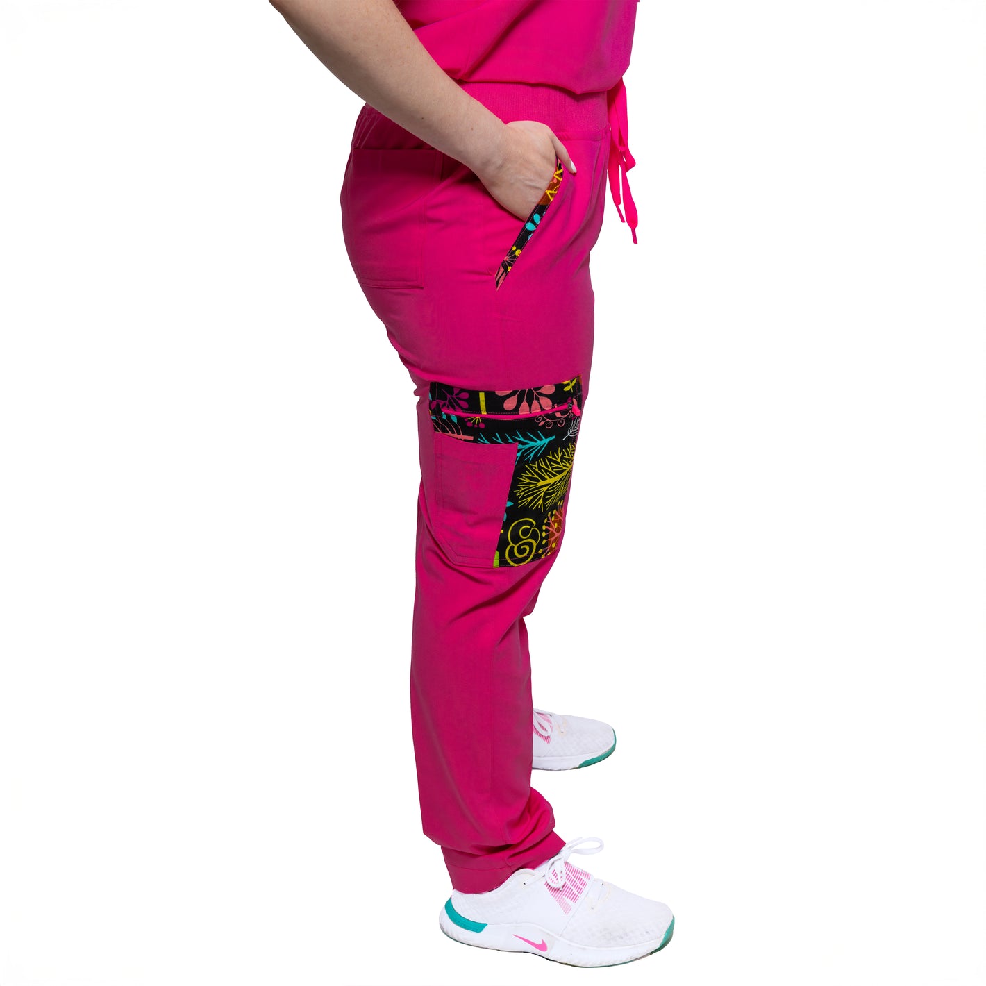 A person wearing pink female Nia Scrub Pant with decorative detail on the knee area.