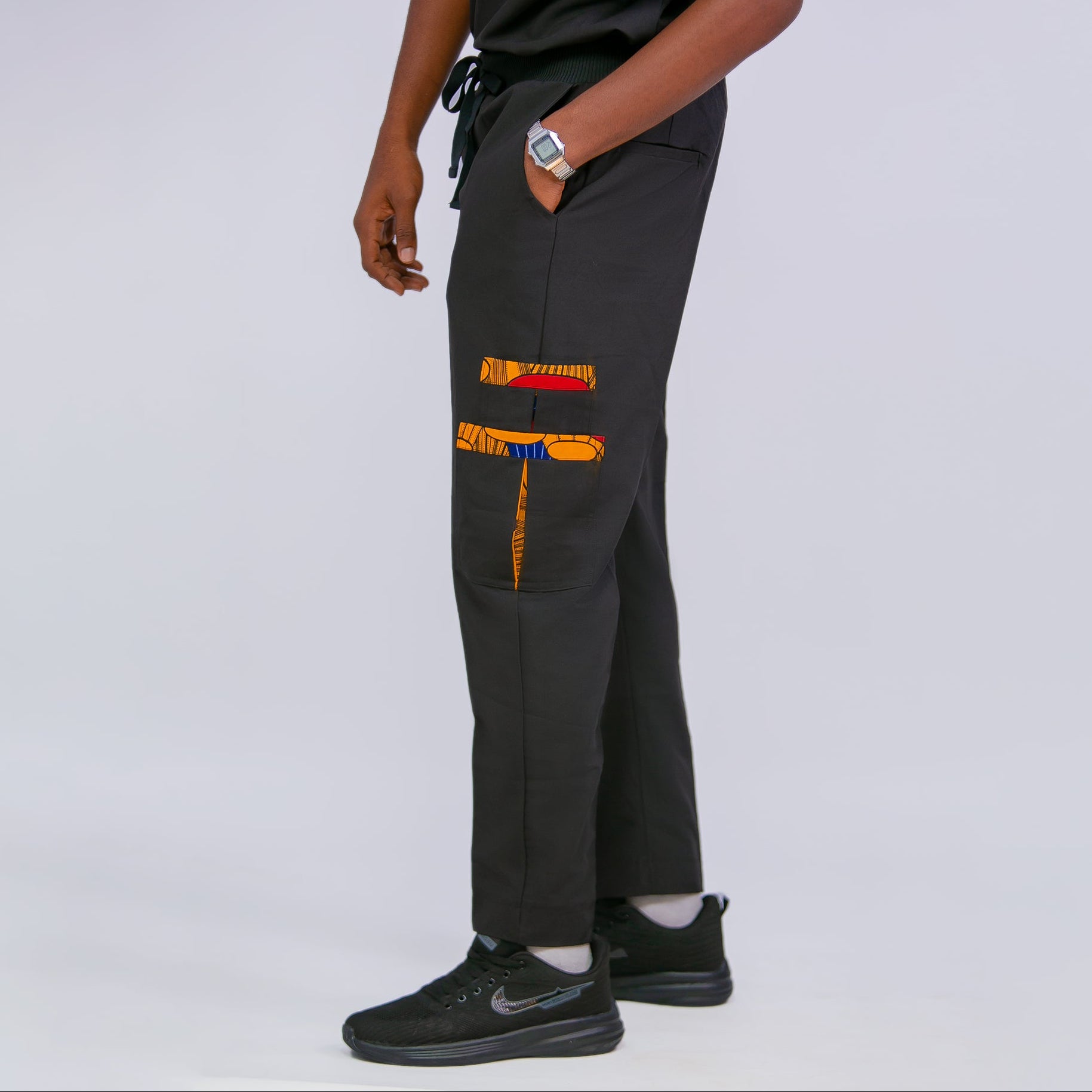 Person wearing black scrub pants with colorful design on a white background