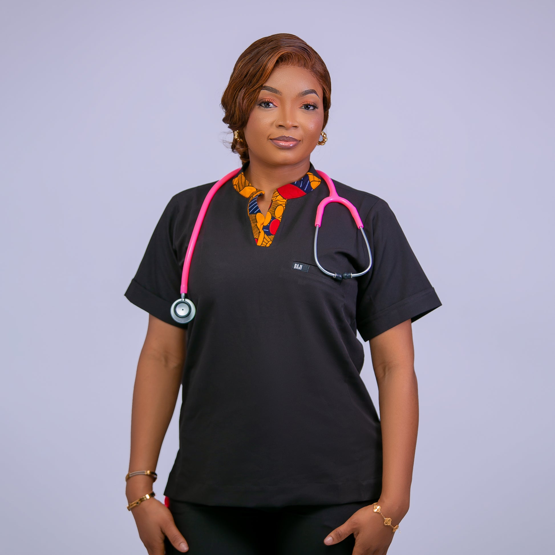 Person wearing a black scrub top with a pink stethoscope against a light purple background