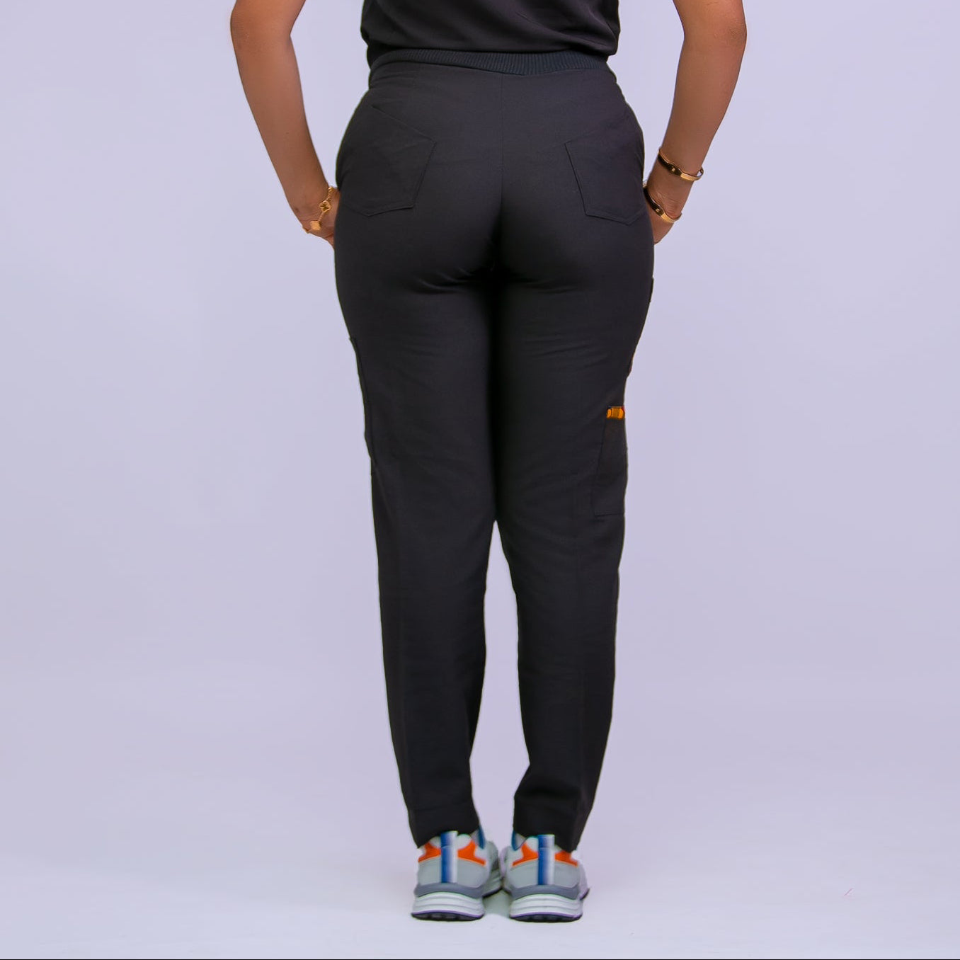 Person wearing a black  scrub outfit on a plain background